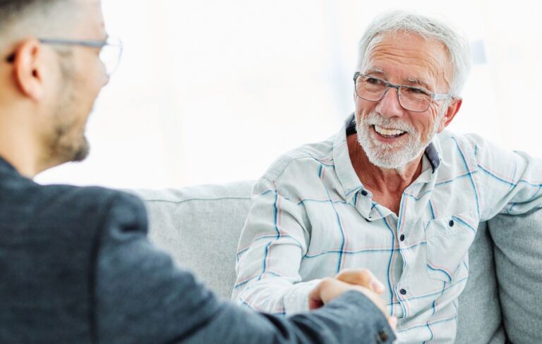 Happy senior man shaking hands with a financial professional