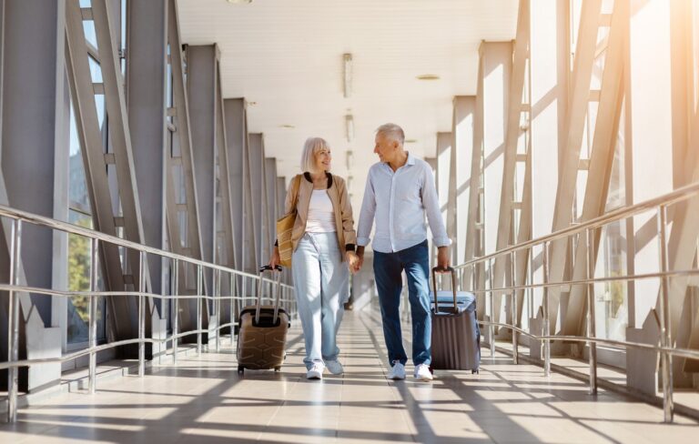 Happy senior couple walking through an airport with luggage