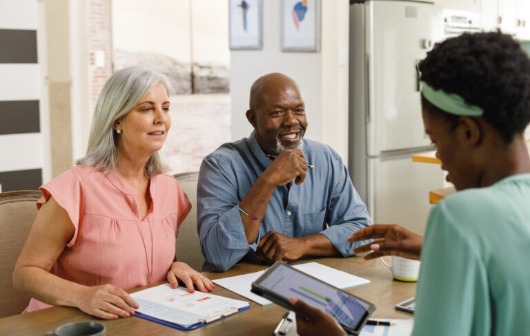 Female financial adviser using a tablet and talking to a senior couple