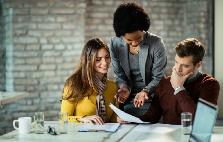 A female financial planner consulting a middle-aged couple while looking at paperwork